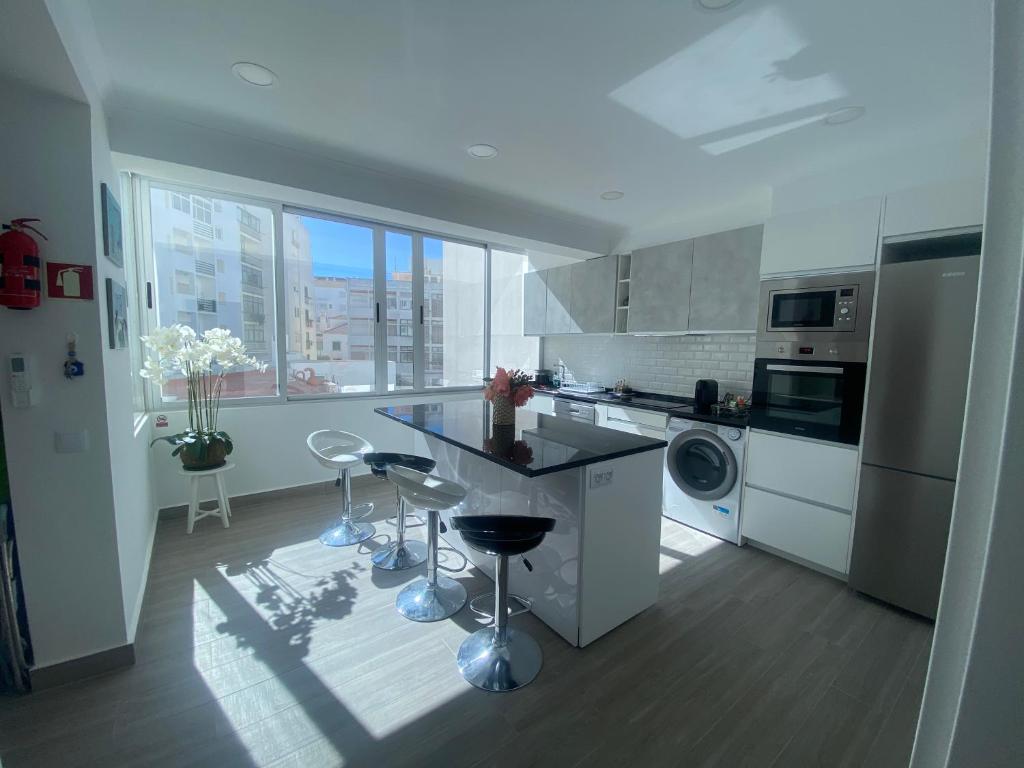 a white kitchen with a counter and stools in it at DyLary in Armação de Pêra