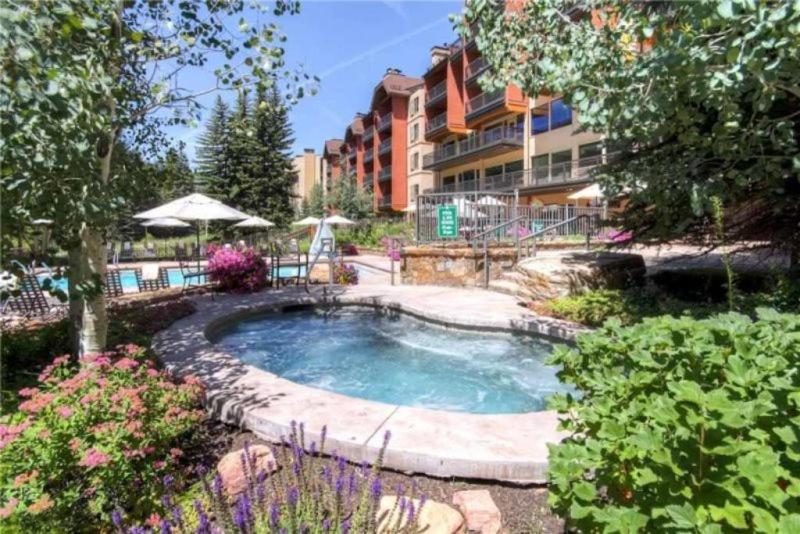 a swimming pool in a yard with a building at Ski In, Ski Out 2 Bedroom Vacation Rental In The Heart Of Lionshead Village With Heated Slope Side Pool And Hot Tub in Vail