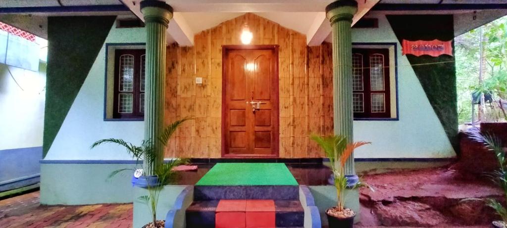 a house with a wooden door and two potted plants at Nature Inn Cottages in Gokarna