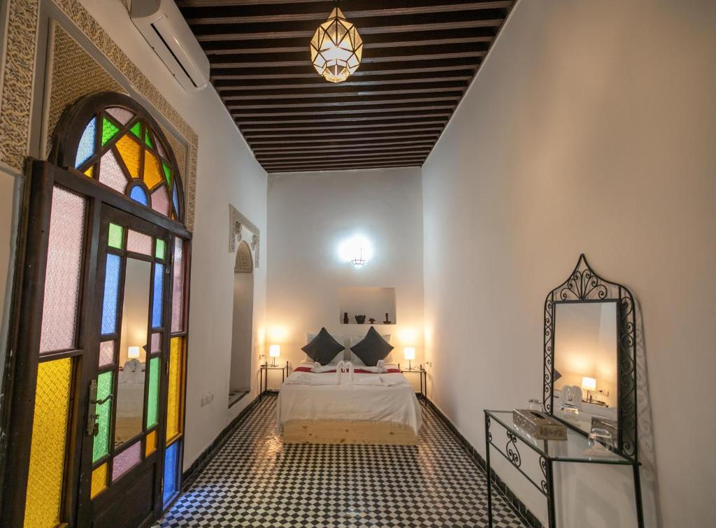 a bedroom with a bed and a stained glass window at Riad Nashira in Fès