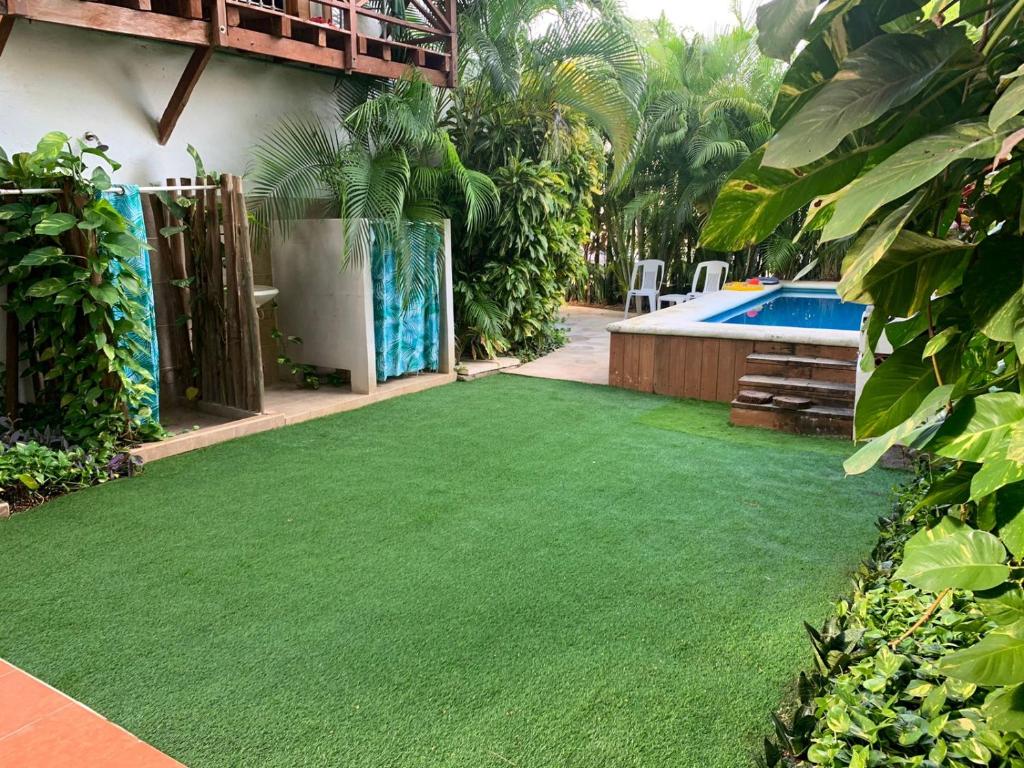 Un jardín con césped verde junto a una piscina. en Casa Nona Rosa, en Cancún