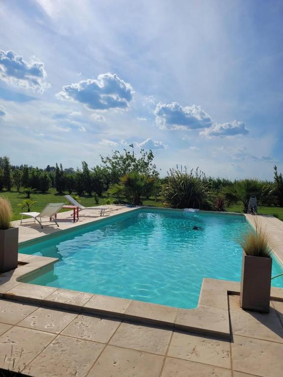 une piscine avec de l'eau bleue dans une cour dans l'établissement Villa provençale à Arles avec piscine privée et vue jardin., à Arles