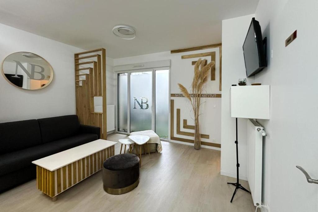 a living room with a black couch and a tv at Spacieux appart terrasse métro hôpital 4pers wifi in Villejuif