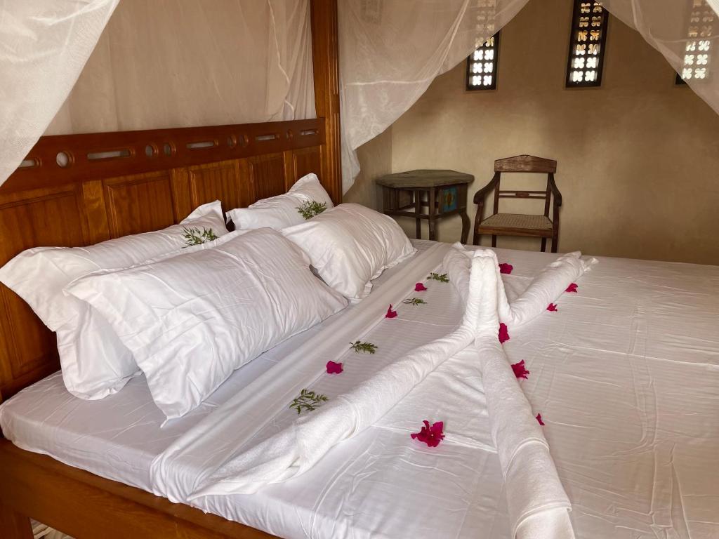 a bed with white sheets and pink flowers on it at Umma House in Lamu