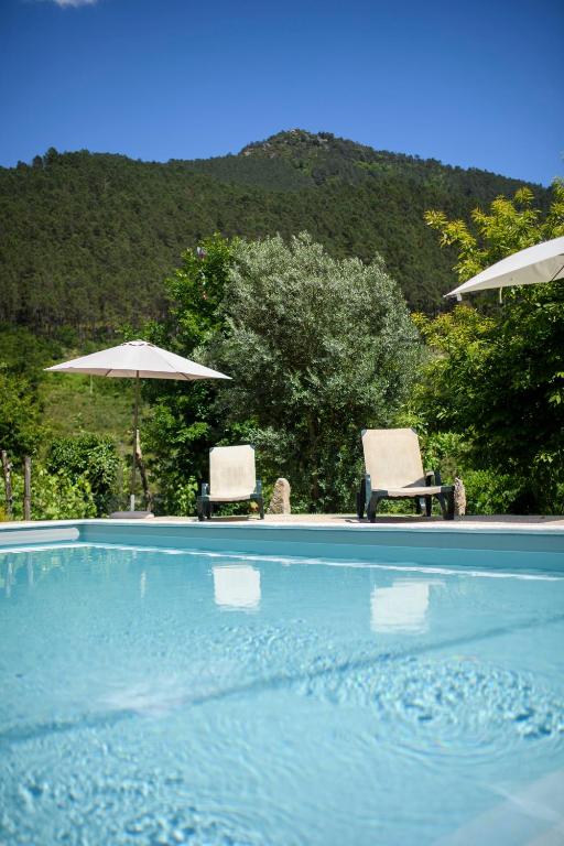 two chairs and umbrellas next to a swimming pool at Afonso's House Gerês I in Braga