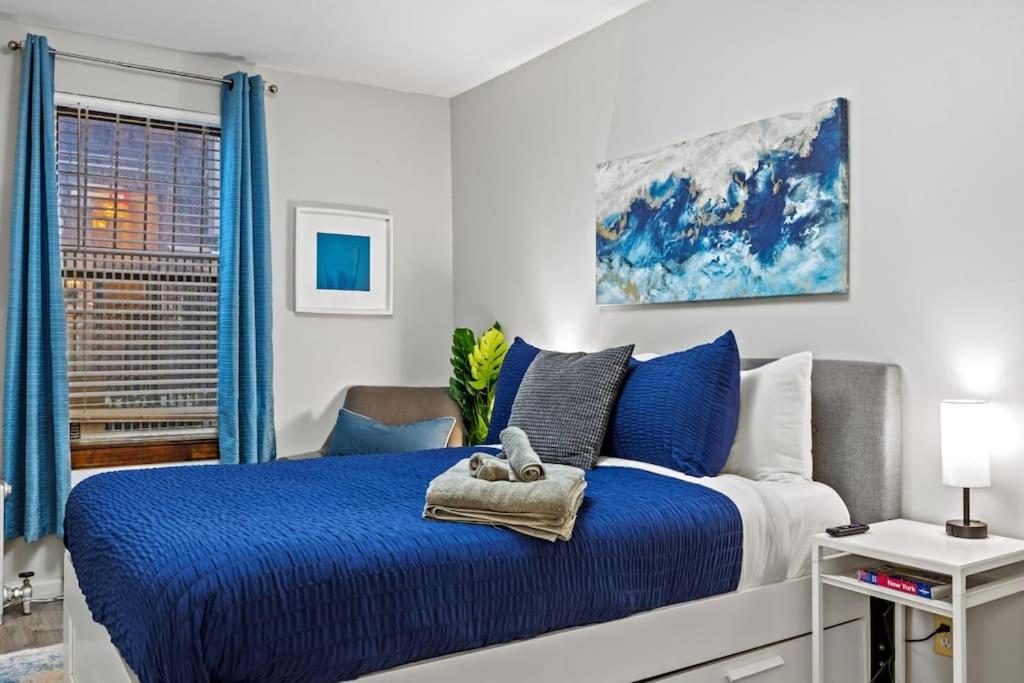 a bedroom with a blue and white bed and a window at Central Location Studio Walk to Times Square in New York