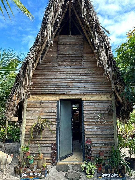 a house with a thatched roof with a cat standing in front at Flor da Aldeia Eco Hospedaria in Camaçari