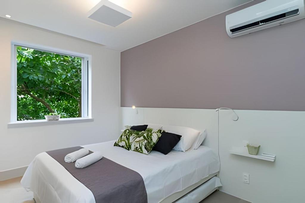 a white bedroom with a bed and a window at Apto Copacabana 200 da Praia - Suíte + Lava&Seca in Rio de Janeiro