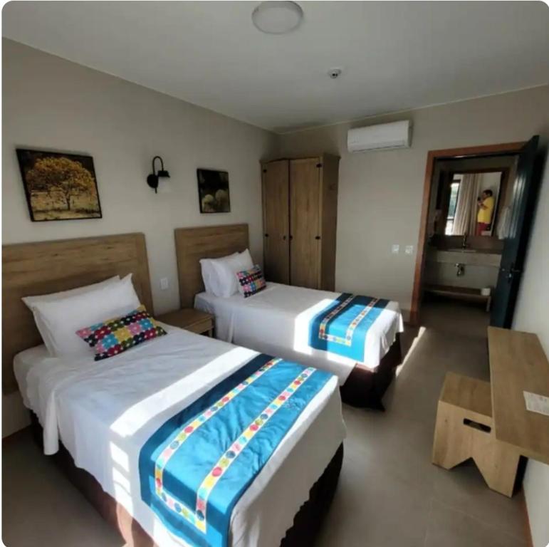a hotel room with two beds and a table at Pirenópolis Quinta Santa Bárbara - Apto 2q para 06 pessoas - Térreo in Pirenópolis