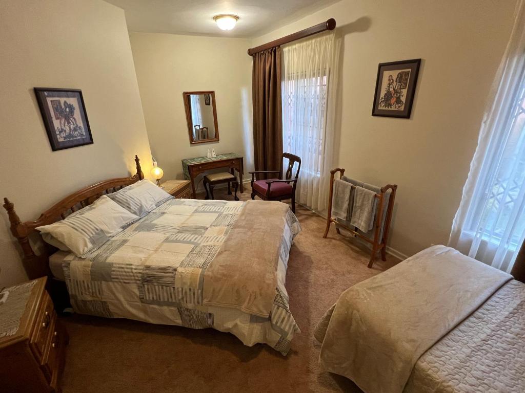 a bedroom with two beds and a table and a chair at Bult-Op1 in Bloemfontein