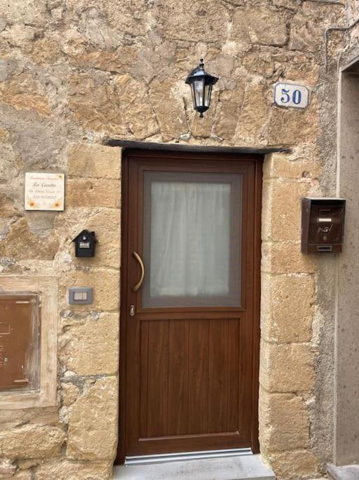 a stone building with a wooden door with a sign on it at La Casetta in Grotte di Castro