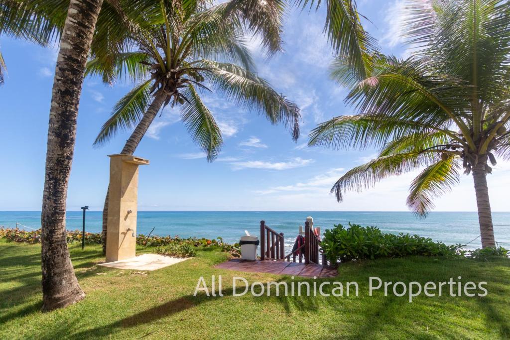 a woman sitting on a bench looking at the ocean at Victorian Condominium, Cabarete! in Cabarete