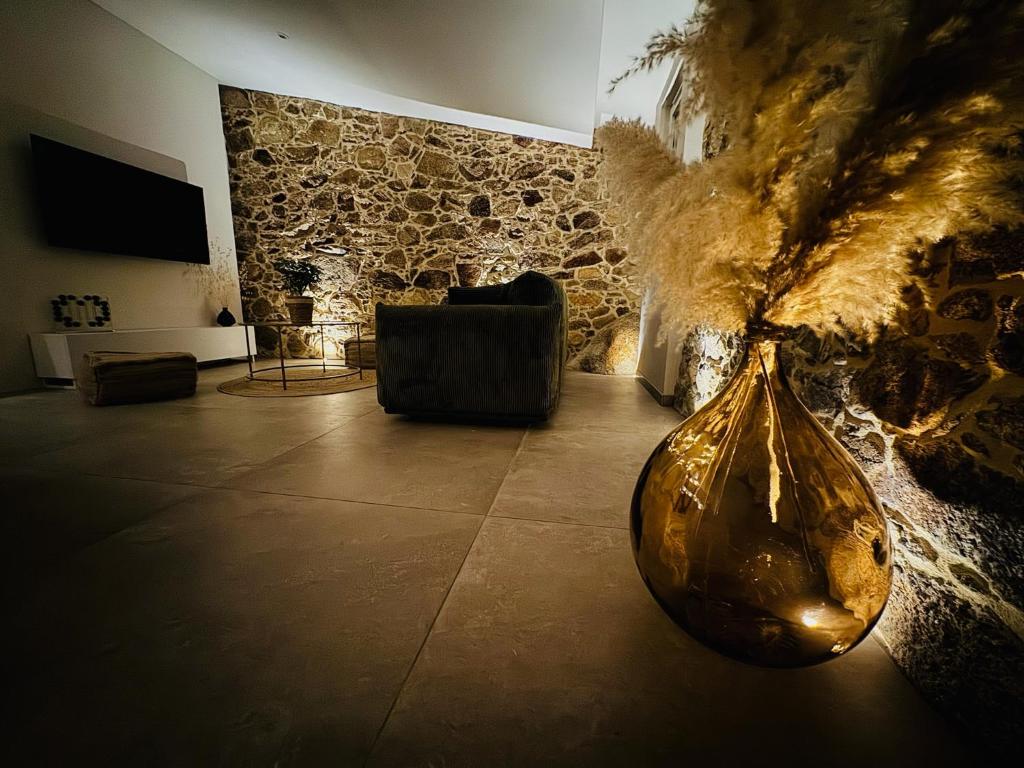 - un salon avec un mur en pierre et un vase dans l'établissement Charmante maison en pierre vue mer et piscine privée, à Cuttoli-Corticchiato