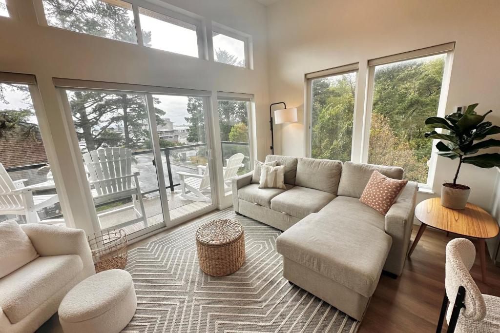 Una sala de estar con un sofá y sillas y ventanas. en Bay View Loft, en Lincoln City