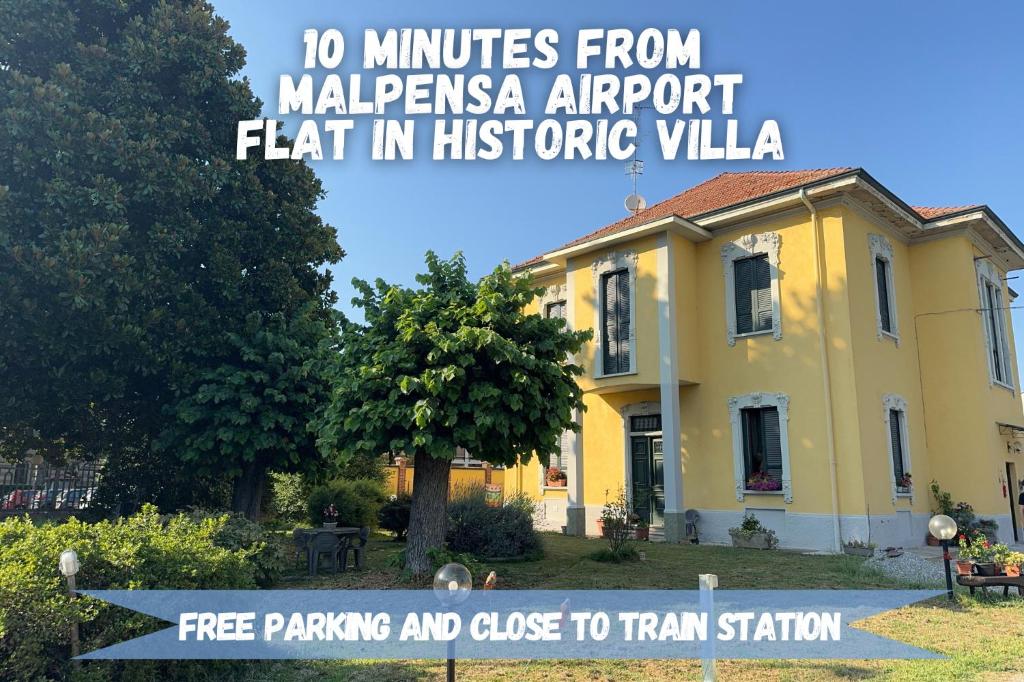 een geel huis met een bord ervoor bij 10' Malpensa Airport, alongside Train Station in Casorate Sempione