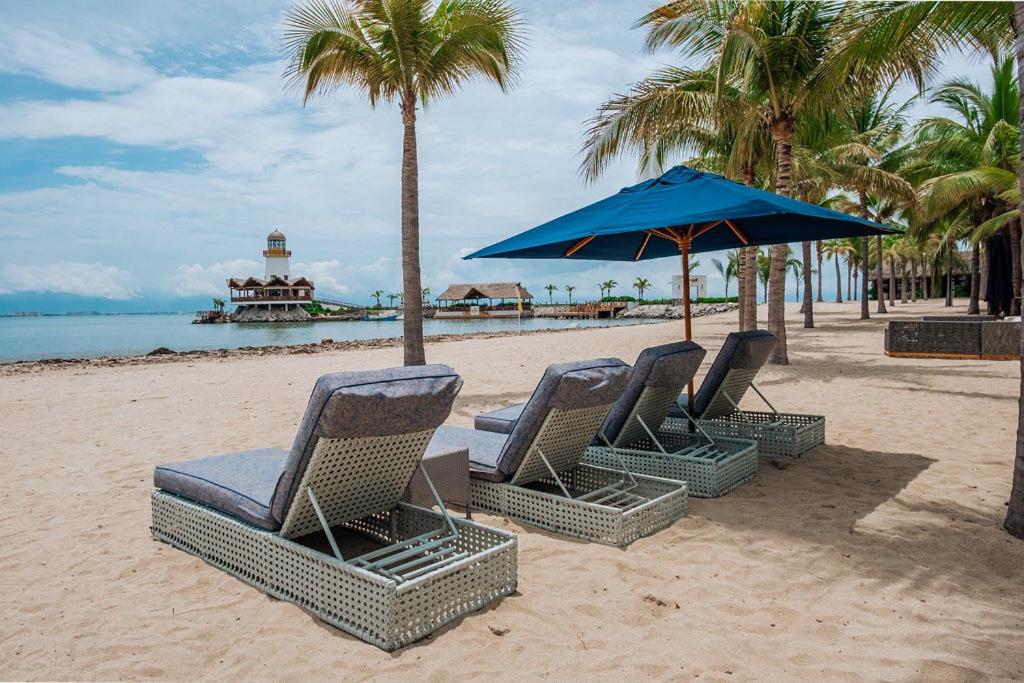 a group of chairs and an umbrella on a beach at Tropical Oasis with cook and Housekeeping service INCLUDED Private Pool BBQ Beach Access in Cruz de Huanacaxtle