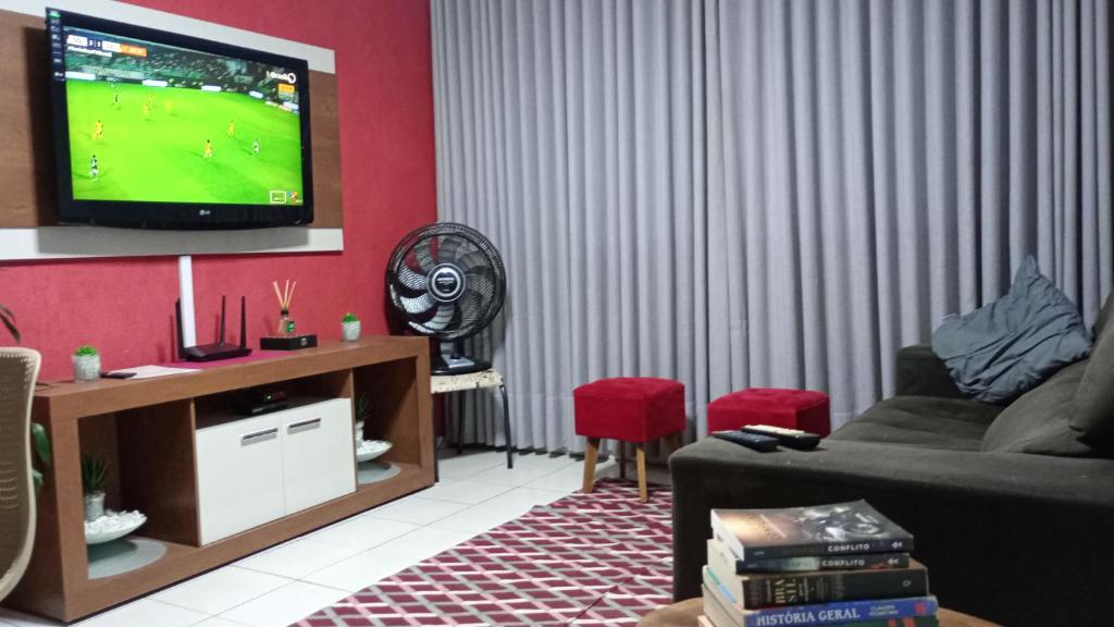 ein Wohnzimmer mit einem Sofa und einem Fernseher an der Wand in der Unterkunft Apto Completo Aparecida de Goiânia in Aparecida de Goiania
