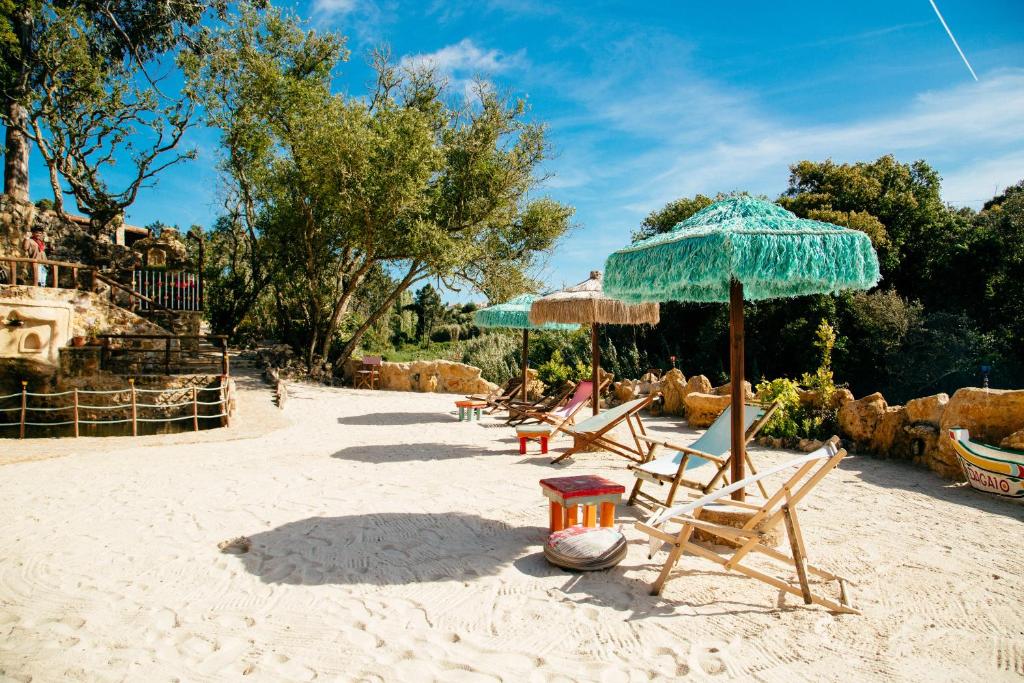 - un groupe de chaises longues et de parasols sur une plage dans l'établissement EcoNature Dagaio Handmade Paradise, à Ericeira