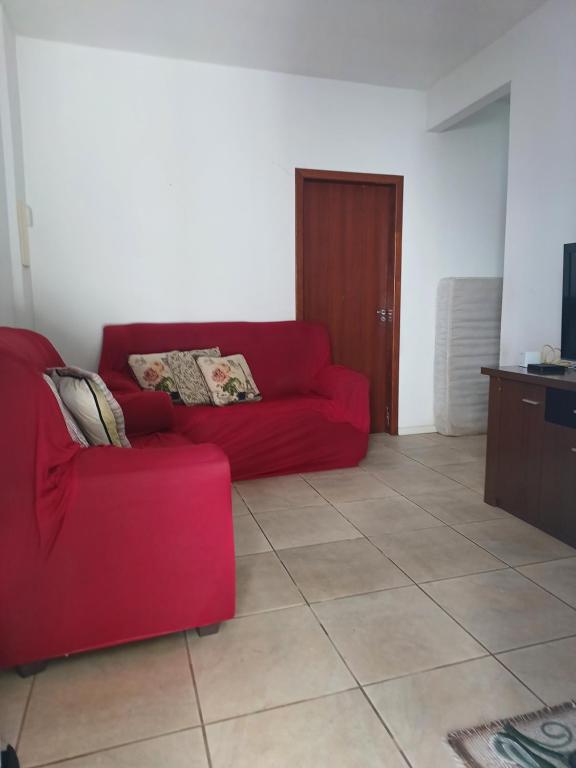 ein rotes Sofa im Wohnzimmer in der Unterkunft CASA ALOJAMENTO EMPRESAS ou GRUPO ÚNICO in Porto Alegre