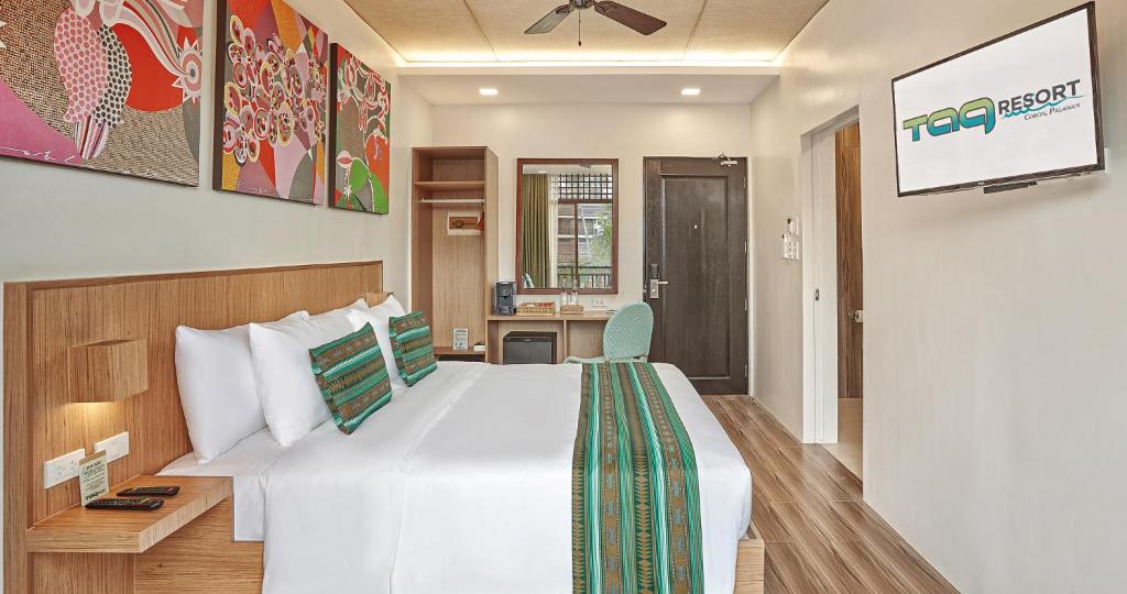 a bedroom with a large white bed and a tv at Tag Resort in Coron