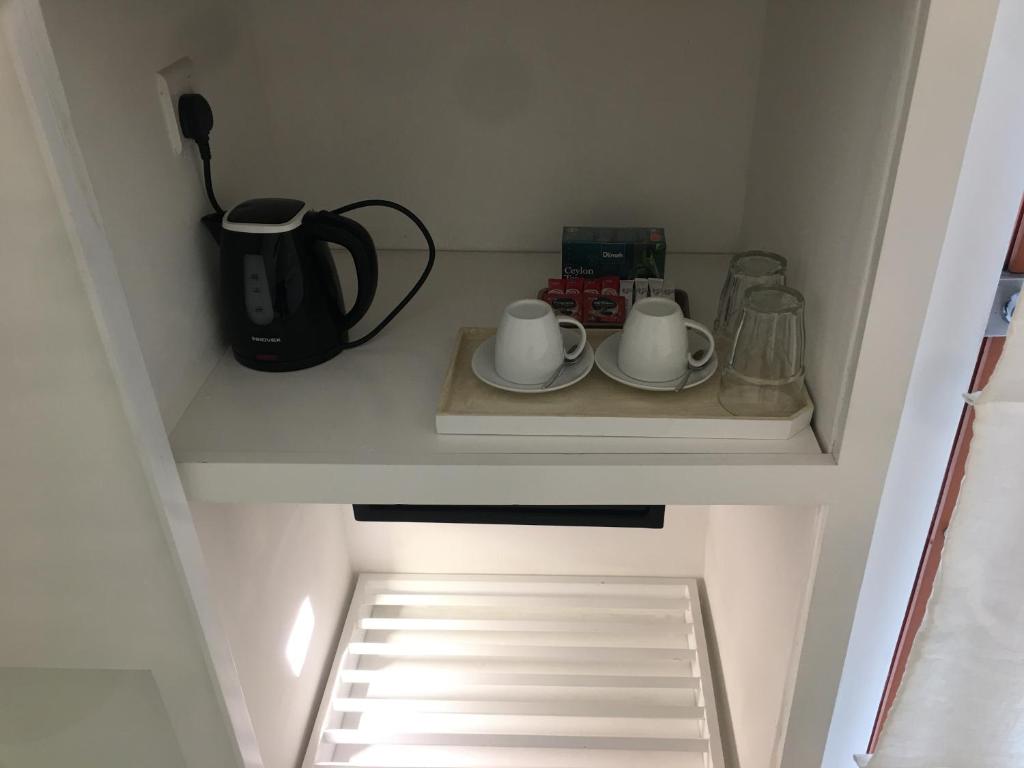 a cupboard with two cups and a coffee maker on a shelf at Saffron Robes Living in Hikkaduwa