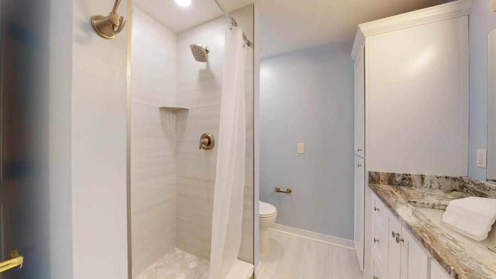 a white bathroom with a shower and a toilet at ALWAYS TURTLE CRAWL home in Jekyll Island