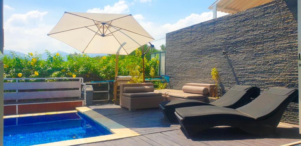eine Terrasse mit Stühlen und Sonnenschirm und ein Pool in der Unterkunft Meninting Beach Villa, 3 bedroom in Montongbuwoh