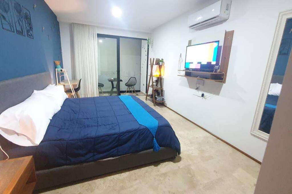 a bedroom with a blue bed and a television at Estudio de playa Monpal in Playa del Carmen