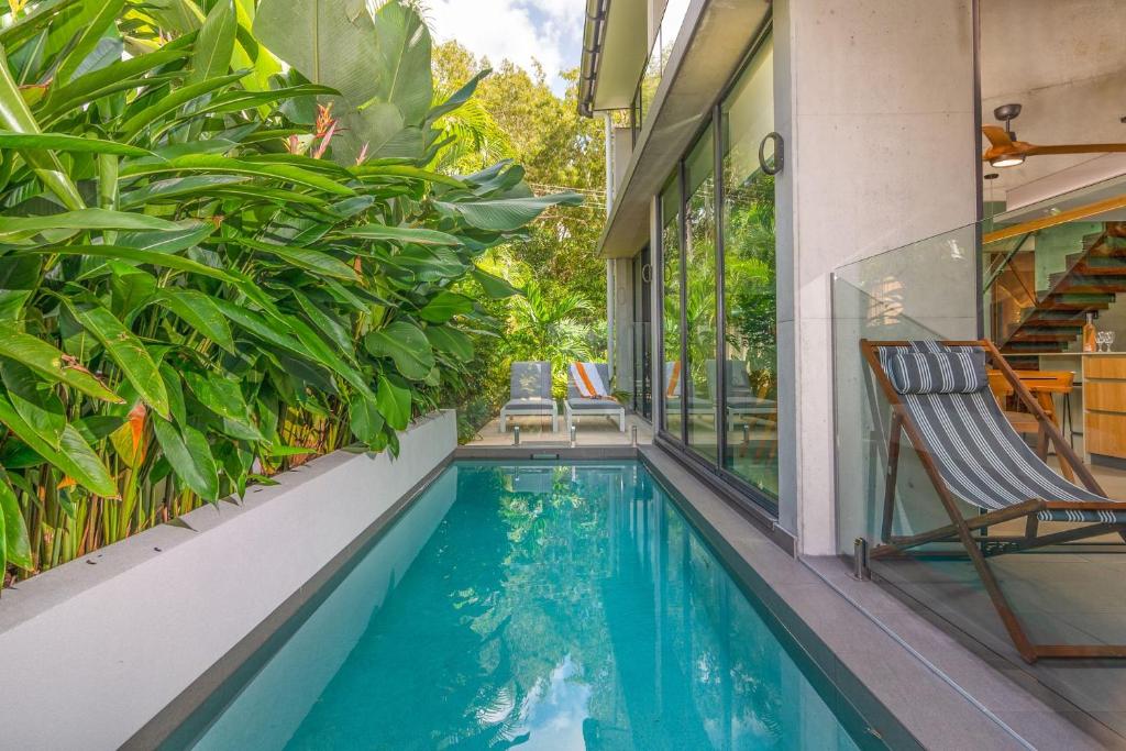 a swimming pool with chairs and plants on a house at Aria Villa 2 Port Douglas in Port Douglas