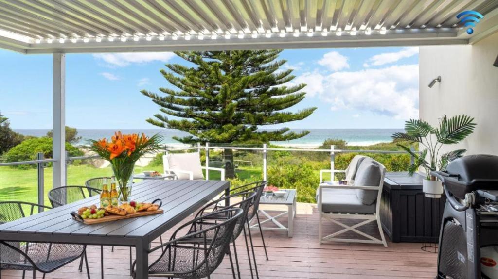 a patio with a table and chairs and a view of the ocean at Jones Waterfront Beach Escape in Kiama Downs