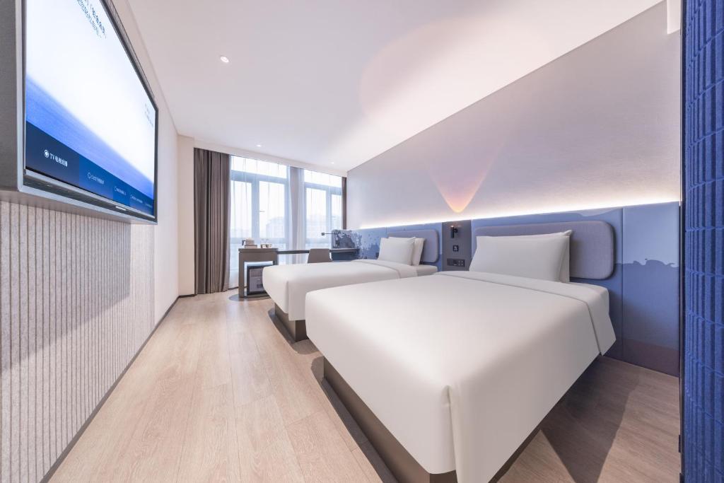 揚州市にあるAtour Light Hotel Yangzhou Dongguan Street Ancient Canal Wharfのベッド2台とテレビがあるホテルの部屋