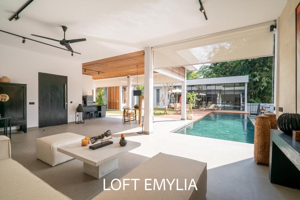 an open living room with a pool in a house at Rouge - Loft Emylia in Ubud