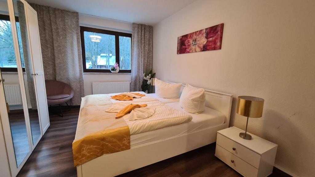 a bedroom with a white bed with a lamp and a window at Ferienwohnungen Am Bühlwald in Eibenstock