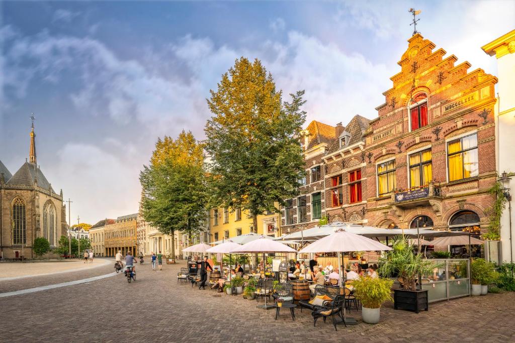 een stadsstraat met tafels, stoelen en gebouwen bij Grand Boutique Hotel-Restaurant Huis Vermeer in Deventer