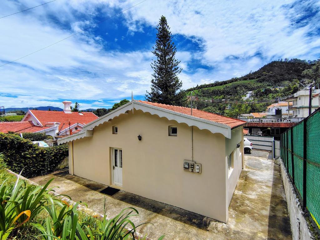 a small white house with red roof at The Cosy Cottage in Coonoor