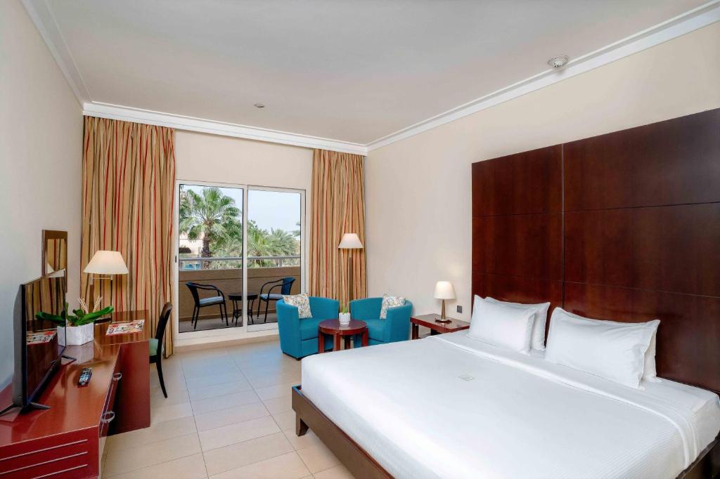 a hotel room with a bed and a balcony at Metropolitan Al Mafraq Hotel in Abu Dhabi