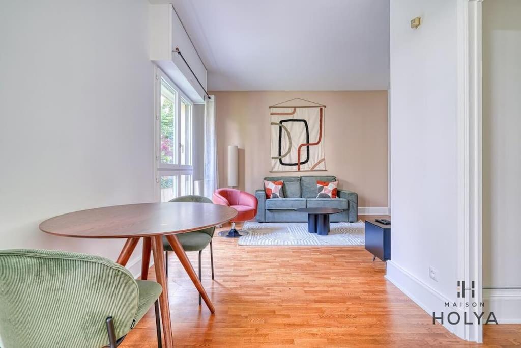 un salon avec une table et des chaises en bois dans l'établissement Le Flamboyant - En bordure de Paris - 340B, à Versailles