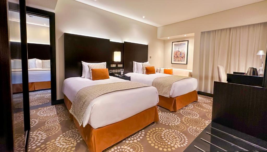 a hotel room with two beds and a television at Crowne Plaza Bahrain by IHG in Manama
