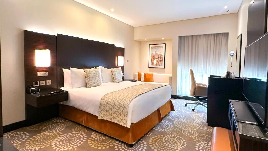 a hotel room with a bed and a television at Crowne Plaza Bahrain by IHG in Manama