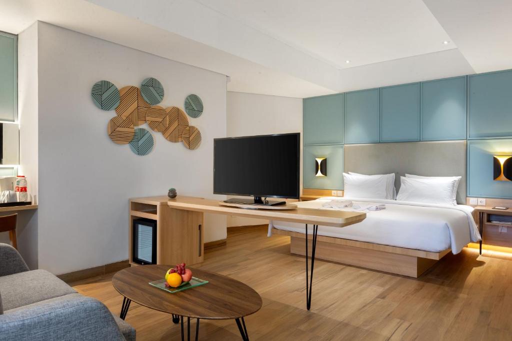 een slaapkamer met een bed en een bureau met een televisie bij Hotel Santika Pasir Koja Bandung in Bandung