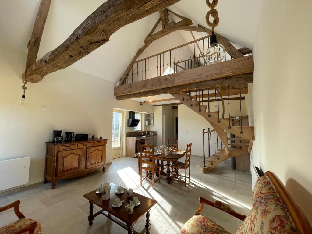a living room with a staircase and a table at Ecuries Tourangelles in Bréhémont