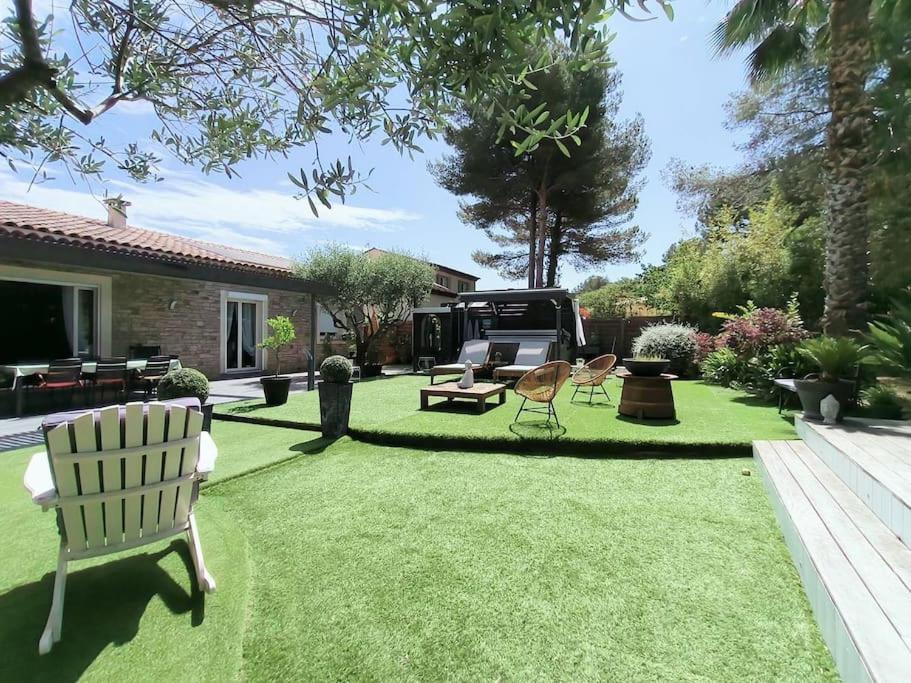 une cour avec un banc blanc, une table et des chaises dans l'établissement FREJUS-Villa indépendante piscine et jaccuzzi, à Fréjus