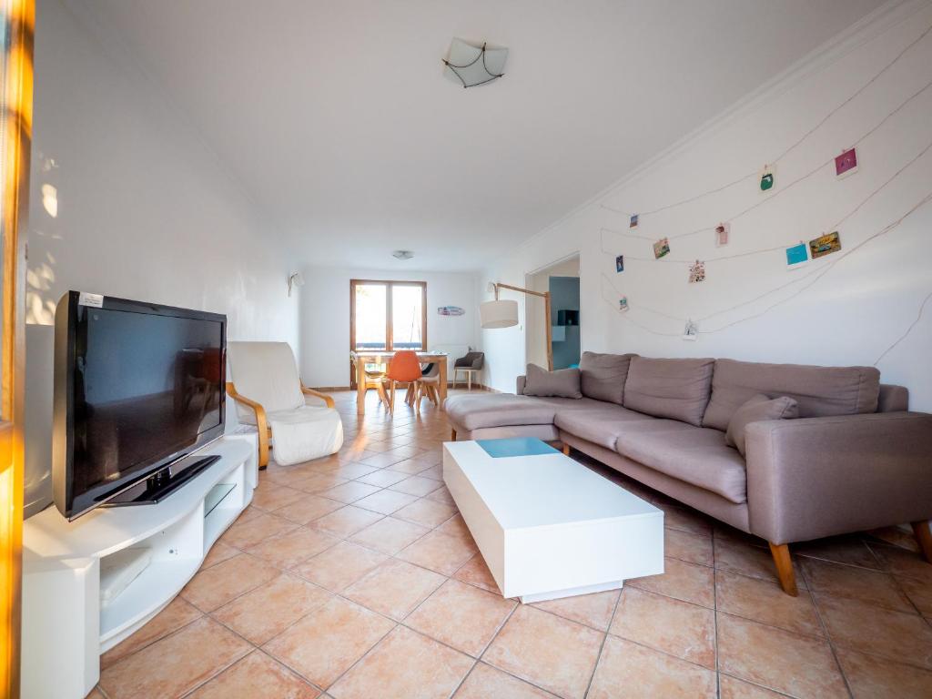 un salon avec un canapé et une télévision à écran plat dans l'établissement Jolie Villa avec jardin, à Grigny