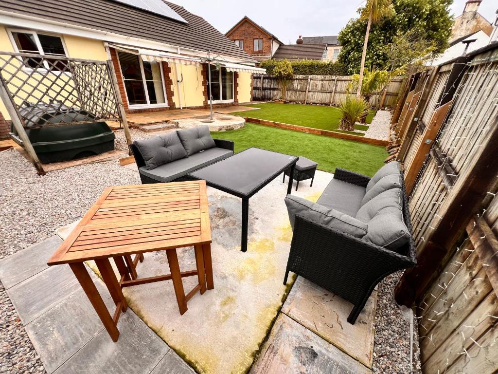 a patio with a table and couches and a table and chairs at Devon Bungalow in Holsworthy