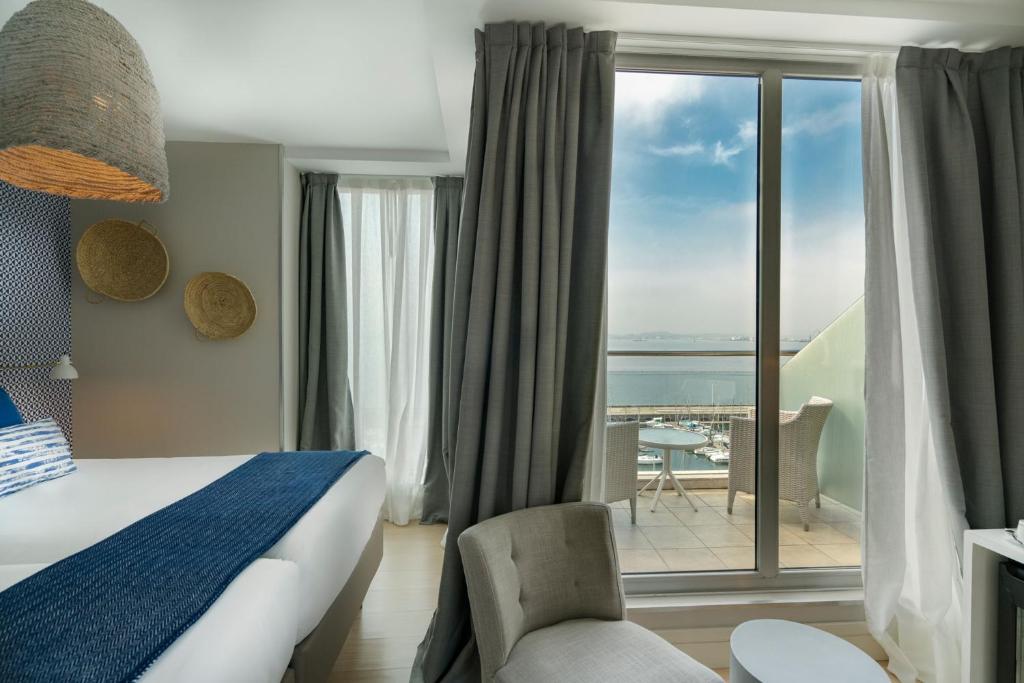 a hotel room with a bed and a view of the ocean at Vincci Puertochico in Santander