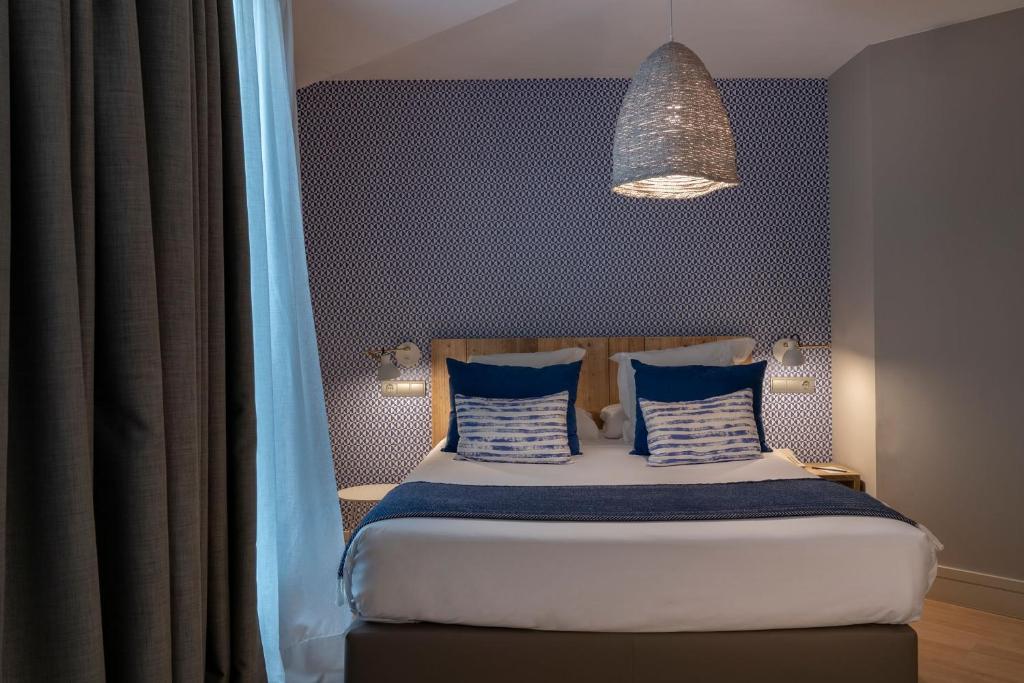 a bedroom with a bed with blue and white pillows at Vincci Puertochico in Santander