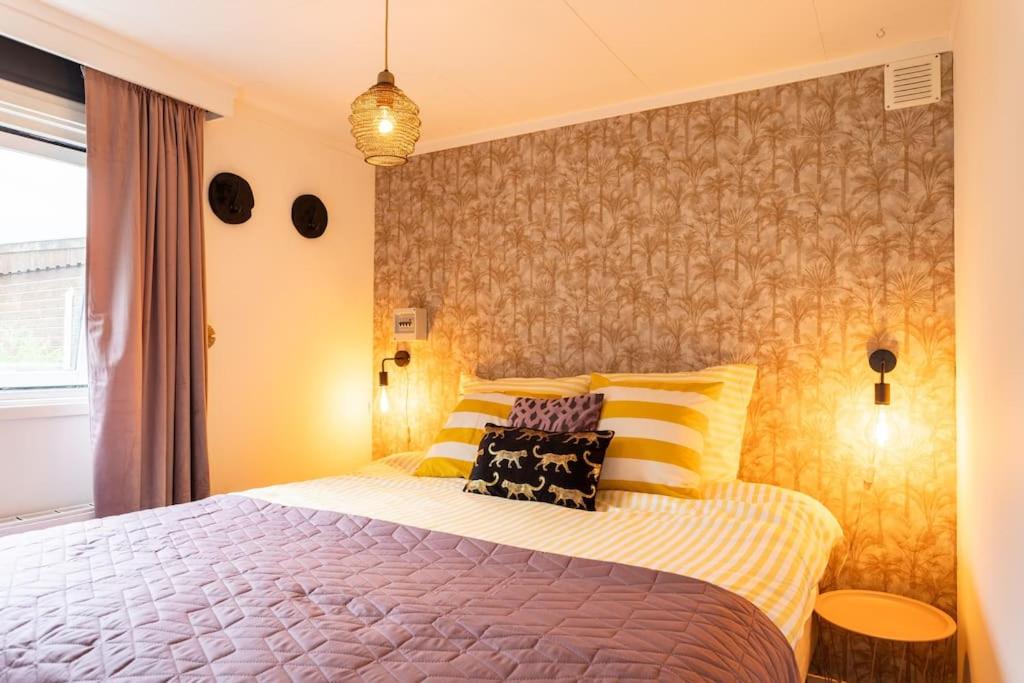 una camera da letto con un letto con cuscini gialli e bianchi di Boutique Chalet Putten op de Veluwe a Krachtighuizen