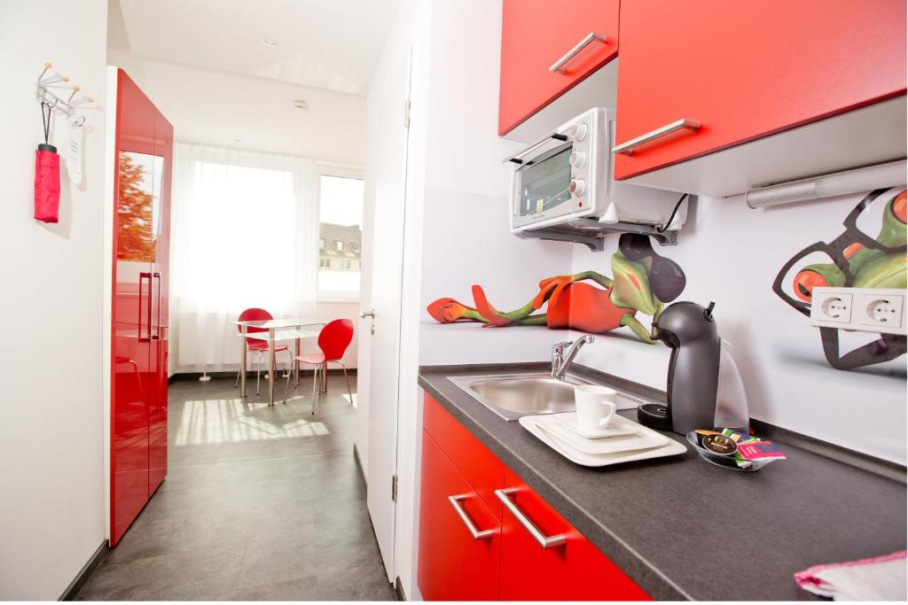 a kitchen with red cabinets and a sink at Design Sleepy Cologne in Cologne