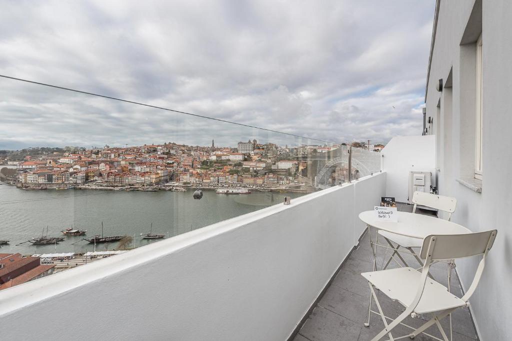 ein Balkon mit zwei Stühlen und einem Tisch und einer Aussicht in der Unterkunft GuestReady - Riverview Douro Balcony in Vila Nova de Gaia