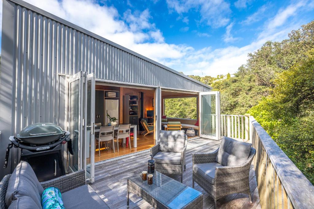 a deck with chairs and a grill on a house at Feathers Nest, Oneroa - Be My Guest Waiheke in Oneroa